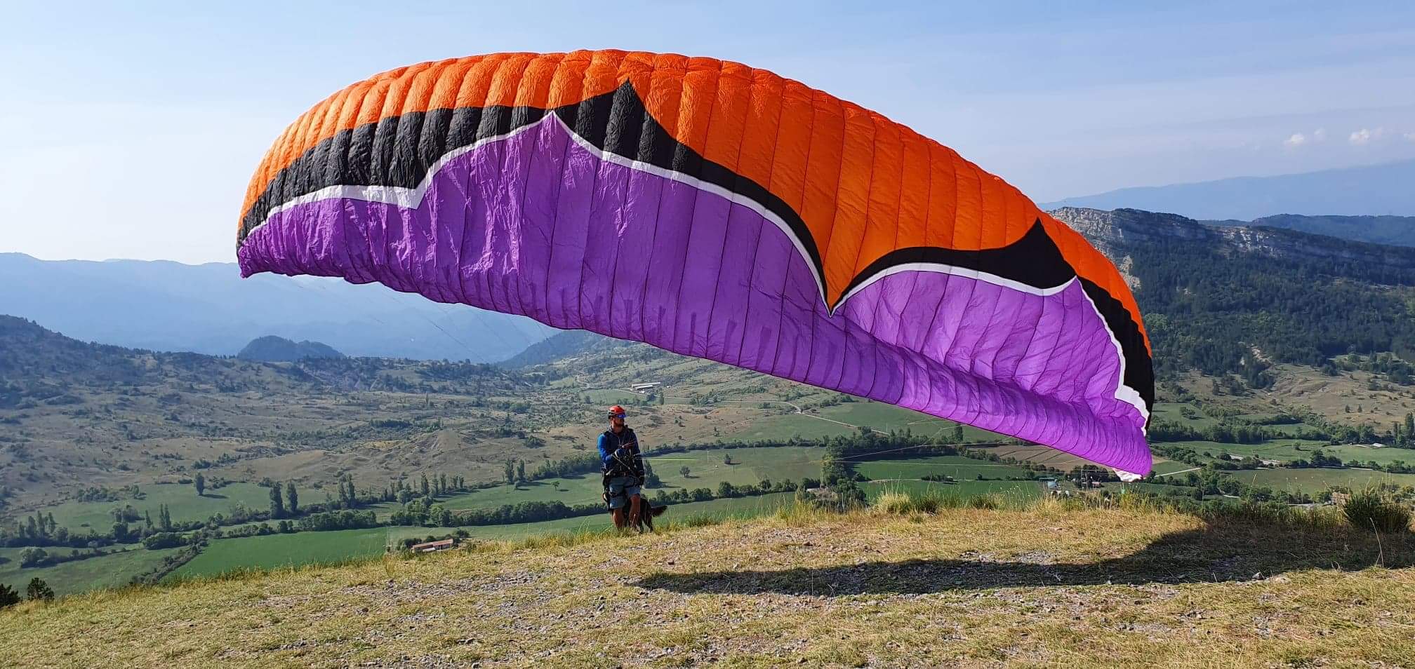 Pilote travaillant le gonflage de sa voile de parapente sur un décollage